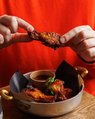 A hand holding a piece of food with a green leaf on top.